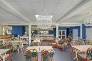 拉尼翁Hôtel Arcadia的餐厅拥有蓝色的墙壁和桌椅