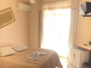 马沙蒂纽Vyalle Hotel的一间卧室设有一张大床和大窗户