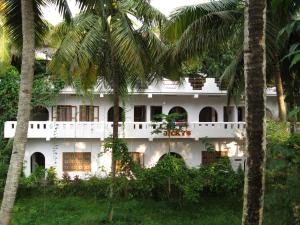 瓦尔卡拉吉奇斯巢旅馆的一座白色的建筑,前面有棕榈树