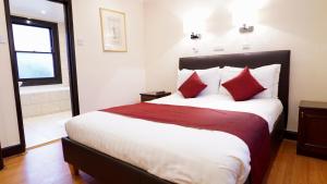 伦敦La Gaffe - Bed and Breakfast的一间卧室配有一张带红色枕头的大床