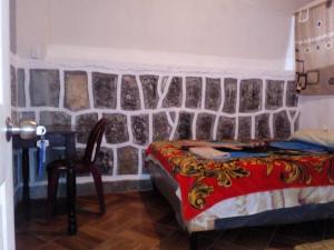圣佩德罗拉拉古纳Casa LLEMO的一间卧室设有石墙、一张床和一把椅子