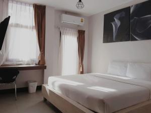 南邦Huglampang Boutique Hotel的卧室配有白色的床和窗户。