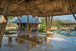 WaikeloMaringi Sumba by Sumba Hospitality Foundation的游泳池旁屋顶下的野餐桌