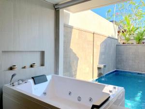 坎古Theanna Villa and Spa Canggu的带浴缸的浴室和游泳池
