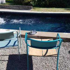 欧坦Moulin Renaudiots - Maison d'hôtes的两张蓝色椅子坐在桌子旁边,水