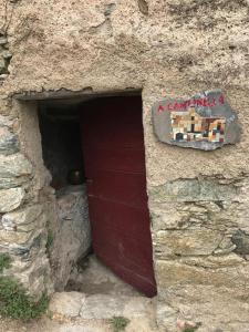 Santa-Lucia-di-Mercurio,A cantinella, une cave a fromage au centre corse的一座石头建筑,有红色的门和标志