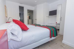 莱昂Slow León Apartamentos Turísticos的卧室配有带红色枕头的白色床