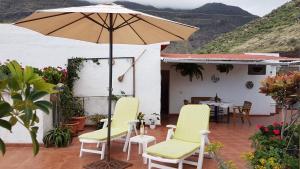 阿格特Ático con gran terraza en el Risco de Agaete-wifi的庭院配有遮阳伞、椅子和桌子。