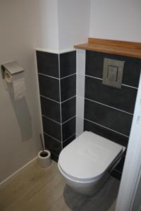 格朗维尔L'ALBATROS的浴室设有白色卫生间和黑色瓷砖墙。