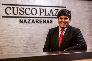库斯科Cusco Plaza Nazarenas的坐在桌子上的男人穿着西装,领带
