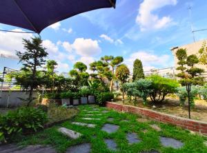 首尔OYO明洞旅館2的花园种有草地和树木,配有遮阳伞