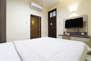 雅加达Hotel Istana Bungur的卧室配有白色的床和平面电视。
