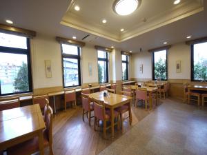 挂川市路线挂川国米酒店的餐厅设有木桌、椅子和窗户。