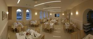 Belvárdgyula贝尔法迪酒店的餐厅设有白色的桌椅和窗户。