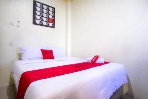 特尔纳特岛RedDoorz near Taman Kota Ternate的卧室配有带红色枕头的大型白色床
