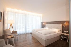 梅拉诺简诗美酒店的卧室配有一张白色的大床和一张桌子