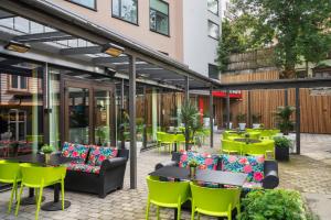 斯塔万格松恩城市酒店的一座带绿色桌椅的庭院和一座建筑