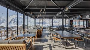 古多里Gudauri Loft Hotel的餐厅配有桌椅,位于山脉的背景中。