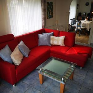 霍瓦赫特Ferienwohnungen und Ferienhaus im Nixenweg的红色沙发、枕头和玻璃茶几