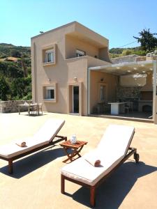 ParaspórionVilla Irini - Cretan Luxury Villa with Amazing View的房屋前的天井上配有2把躺椅