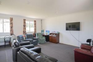 Otatarabeach road holiday park的客厅配有沙发、椅子和平面电视。