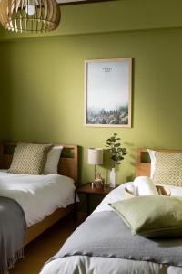 宜野湾市Little Santa的绿墙客房内的两张床