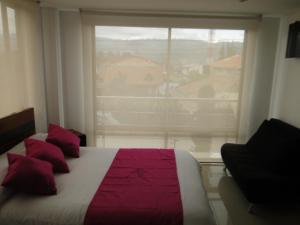 奇亚Hotel Campestre Villa Juliana的一间卧室配有一张带红色枕头的床和一扇窗户
