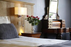 德吕特屯特罗斯的一间卧室配有一张床和一个红色花瓶