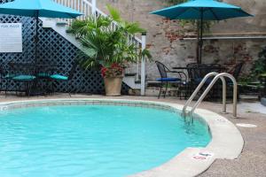 新奥尔良圣皮埃尔法国区酒店的一个带遮阳伞和桌椅的游泳池