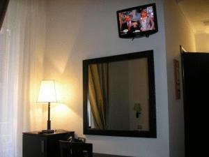 罗马罗马度假村酒店的墙上的镜子,配有电视和灯