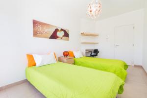 夫塞塔Apartamento Praia Fuzeta的一间卧室配有两张带绿床单的床