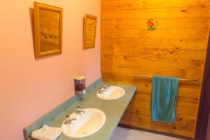 怀托摩洞穴JunoHall Backpackers的一间带两个水槽和木墙的浴室