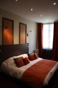 Baugé奥普瑞提格酒店的一间卧室配有一张带橙色枕头的大床