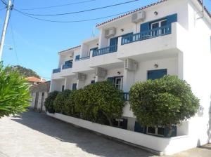 斯卡拉埃雷索Ostria Eressos Rooms的白色的建筑,设有蓝色的阳台,位于街道上