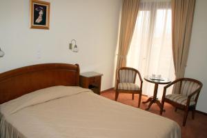 德瓦萨尔米斯酒店的一间卧室配有一张床、两把椅子和一张桌子