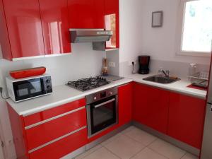 昂代HENDAYE- T2 3*-Wifi-350m plage-terrasse-garage的红色的厨房配有微波炉和炉灶