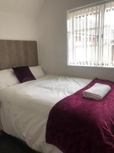 莱斯特Safe Move - 23 Lancaster House的卧室配有白色床和紫色毯子