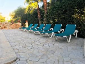 休达德亚Villa para 6 con piscina privada.的坐在庭院里的一排蓝色椅子
