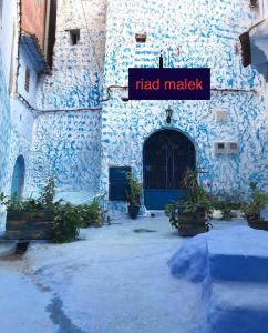 舍夫沙万casa malek的一座有蓝色门和读书标志的建筑,有市场