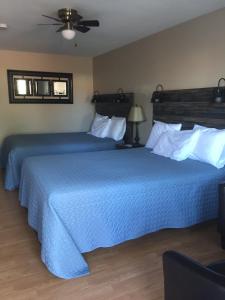 纳尔逊堡卡斯北部套房汽车旅馆的两张位于酒店客房的床,配有蓝色床单