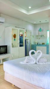 华欣普拉塔纳花园海滩度假酒店的一间卧室配有一张带两个天鹅的床