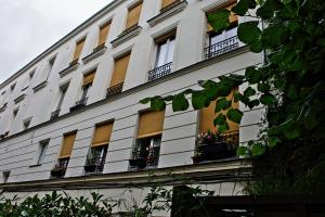 巴黎25 Rue du Télégraphe的白色的建筑,上面有窗户和盆栽植物