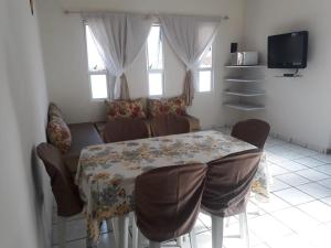 乌巴图巴Condomínio Brisa da Praia - Casas com 2 dormitórios, churrasqueira privativa e 3 vagas de garagem的一间带桌子和沙发的用餐室