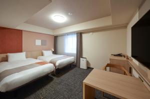松本Iroha Grand Hotel Matsumoto Eki-Mae的酒店客房设有两张床和电视。