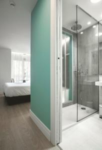 拉科鲁尼亚马德普拉塔酒店的一间带玻璃淋浴的浴室和一张床