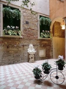 威尼斯洛坎达乐威娜酒店的一间设有两个窗户的房间,窗户上装有植物和雕像