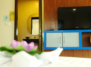 芭东海滩Calypso Patong Hotel的一间设有镜子、电视和粉红色鲜花的客房