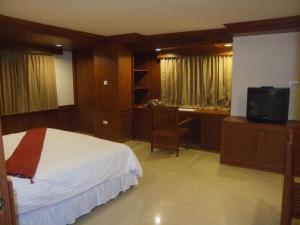 华欣塔纳维特酒店与温泉中心的一间卧室配有一张床、一张书桌和一台电视。