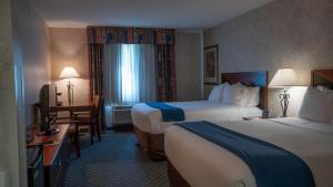 迈尔斯城Miles City Hotel & Suites的酒店客房配有两张床和一张书桌