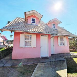 PainelPousada Canto de Pássaros的粉红色的房子,设有白色的窗户和屋顶